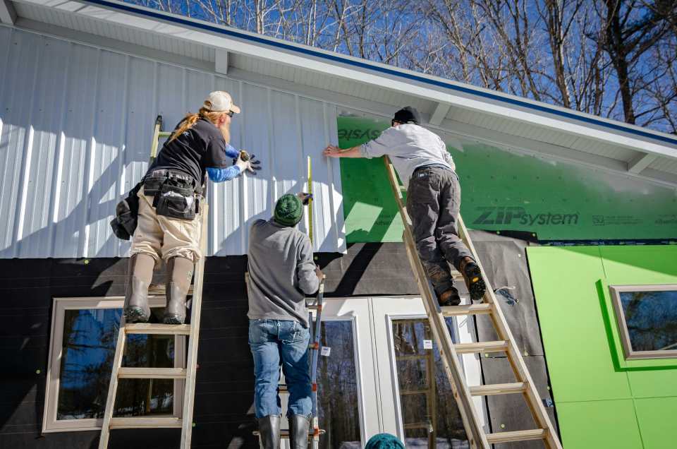 Hombres instalando placas en una fachada 