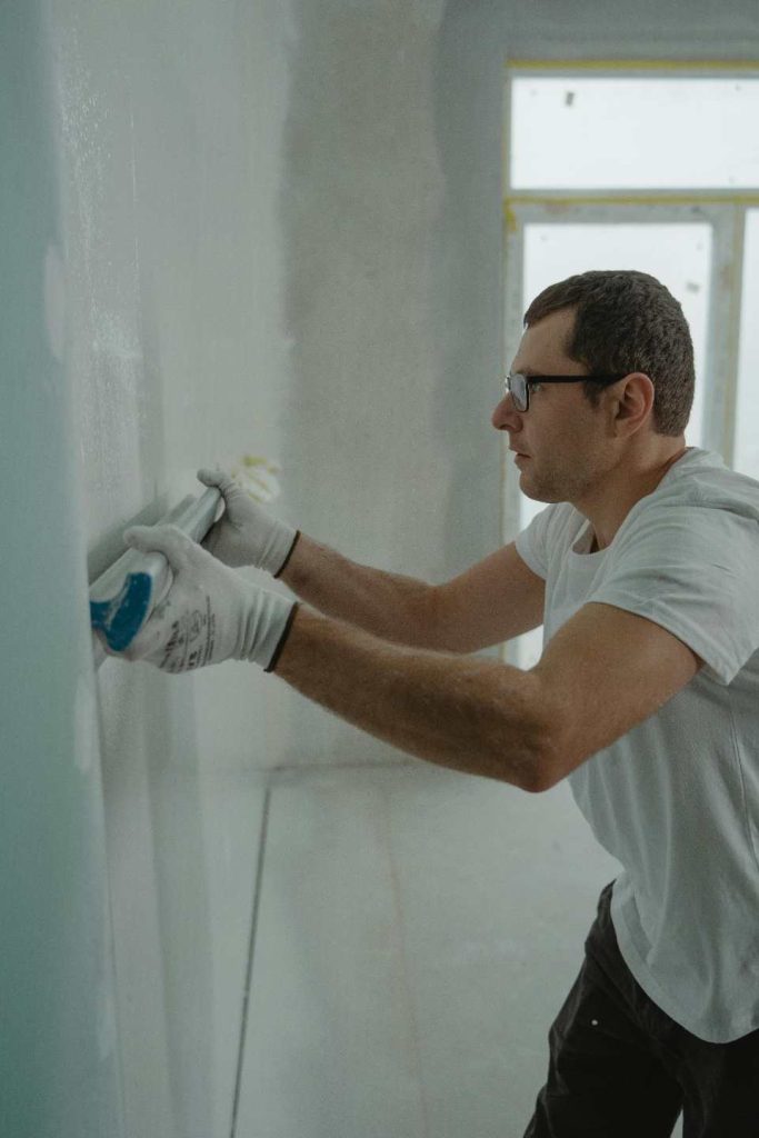 Hombre pasa una barra blanca por una pared